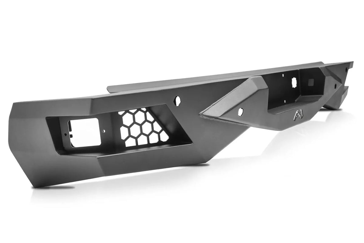 Fab Fours Vengeance rear bumper in black powder coat, angled view, showing the honeycomb sensor/light pocket, angular end cap, and mounting holes