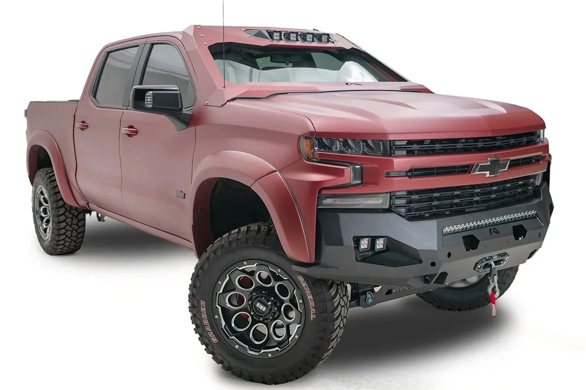 Fab Fours Matrix Front Winch Bumper on a lifted red Chevrolet Silverado 1500, front passenger-side view, with light bar, side cube lights and winch mounted behind the fairlead