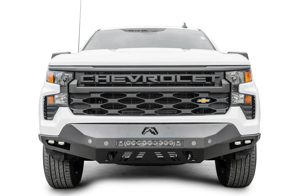 Fab Fours Vengeance front bumper on a white Chevrolet Silverado 1500, straight-on front view, showing the center LED light bar, Fab Fours logo, and lower skid plate cutouts