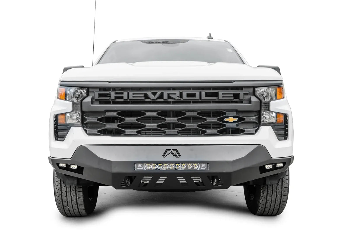 Fab Fours Vengeance front bumper on a white Chevrolet Silverado 1500, straight-on front view, showing the center LED light bar, Fab Fours logo, and corner cube lights