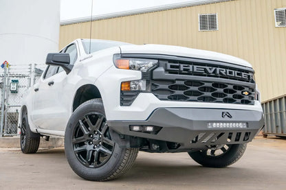 Fab Fours Vengeance front bumper on a white Chevrolet Silverado 1500, front passenger-side three-quarter view outdoors, showing the LED light bar, cube light pods, and skid plate