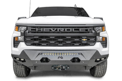 Fab Fours Matrix front bumper on a white Chevrolet Silverado 1500, front view, with LED light bar, dual cube lights in each corner, parking sensors, and winch fairlead