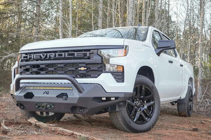 Fab Fours Matrix Front Bumper with pre-runner guard on a white Chevrolet Silverado 1500 outdoors, front driver-side view, showing the angular steel bumper, tubular guard and LED light bar