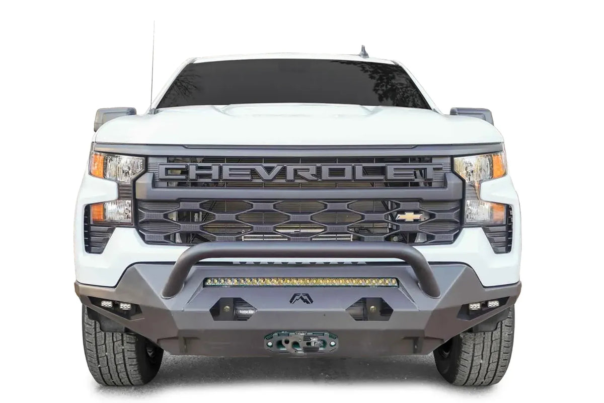 Fab Fours Matrix Front Bumper with pre-runner guard on a white 2022+ Chevrolet Silverado 1500, front view, showing the tubular guard over the LED light bar, side cube lights and winch fairlead