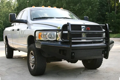 Fab Fours Black Steel front bumper with full guard on a silver Ram 2500, front driver-side three-quarter view outdoors, showing the full grille guard, diamond-plate wings, and headlight hoops