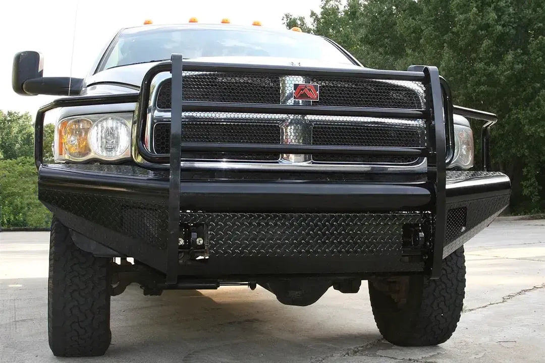Fab Fours Black Steel front bumper with full guard on a silver Ram 2500, straight-on front view outdoors, showing the full grille guard uprights, diamond-plate face, and headlight hoops