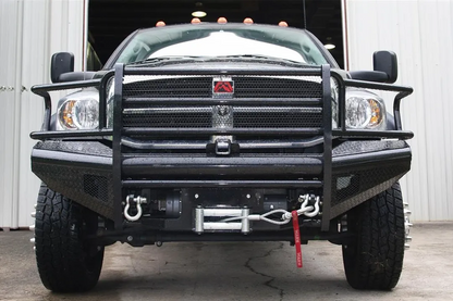 Fab Fours Black Steel front bumper with full guard on a black Ram 2500, straight-on front view, showing the full grille guard, diamond-plate face, winch with D-ring shackles