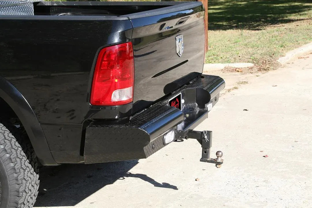 Fab Fours Black Steel Ranch rear bumper with diamond plate on a black Ram 2500 parked in a driveway, rear three-quarter view