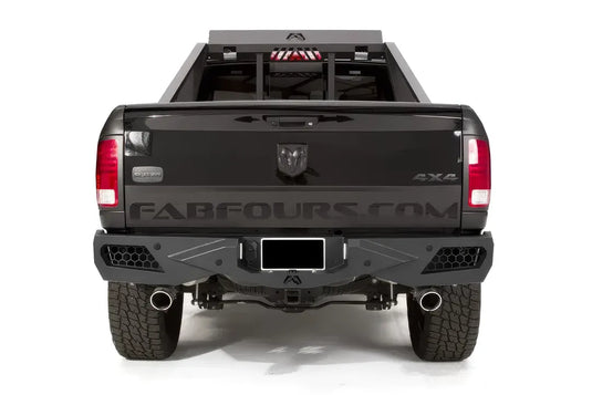 Fab Fours Premium rear bumper on a black Ram 1500 with chase rack, straight rear view, with honeycomb mesh light openings, center license plate mount, and hitch receiver