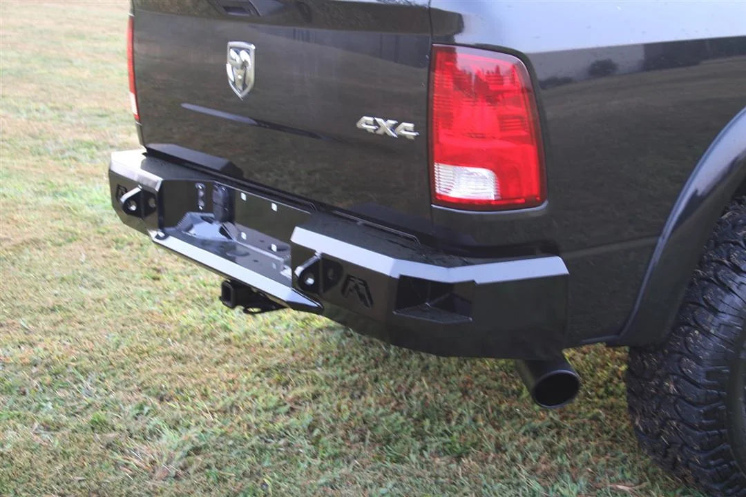 Fab Fours Premium rear bumper on a black Ram 1500, close rear three-quarter view outdoors, showing the angular end cap, Fab Fours logo, and hitch receiver