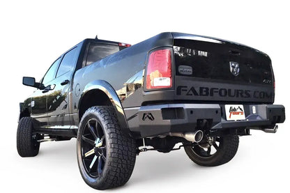 Fab Fours Premium rear bumper on a black Ram 1500, rear driver-side three-quarter view, showing the logo end caps, plate recess, and exhaust cutout