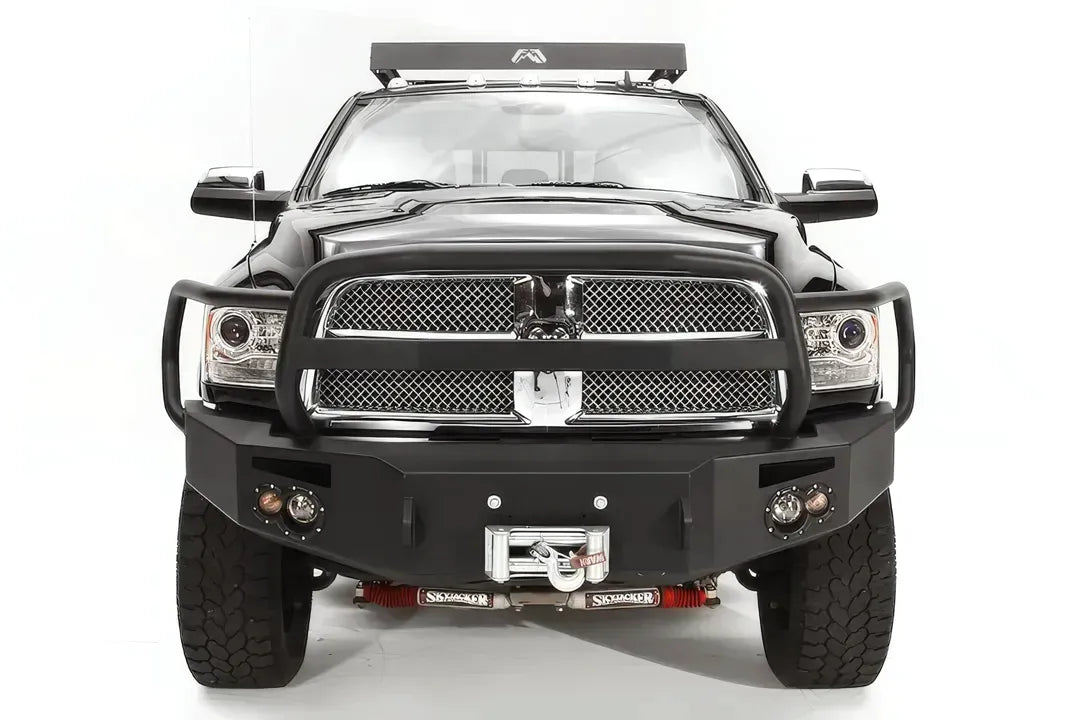 Fab Fours Premium front bumper with full guard on a black Ram 2500, straight-on front view, showing the full grille guard, headlight hoops, and center winch with fairlead