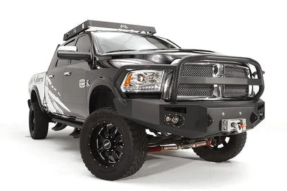 Fab Fours Premium front bumper with full guard on a black Ram 2500, front passenger-side three-quarter view, showing the full grille guard, integrated round lights, and winch opening