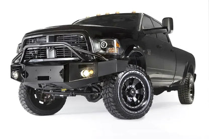Fab Fours Premium front bumper with pre-runner guard on a black Ram 3500 dually, front driver-side three-quarter view, showing the pre-runner hoop, winch plate, and round fog lights