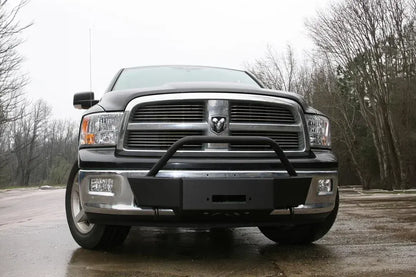 Fab Fours winch mount on a black Ram 1500, straight-on front view outdoors, showing the winch mount plate, tubular hoop, and fairlead opening
