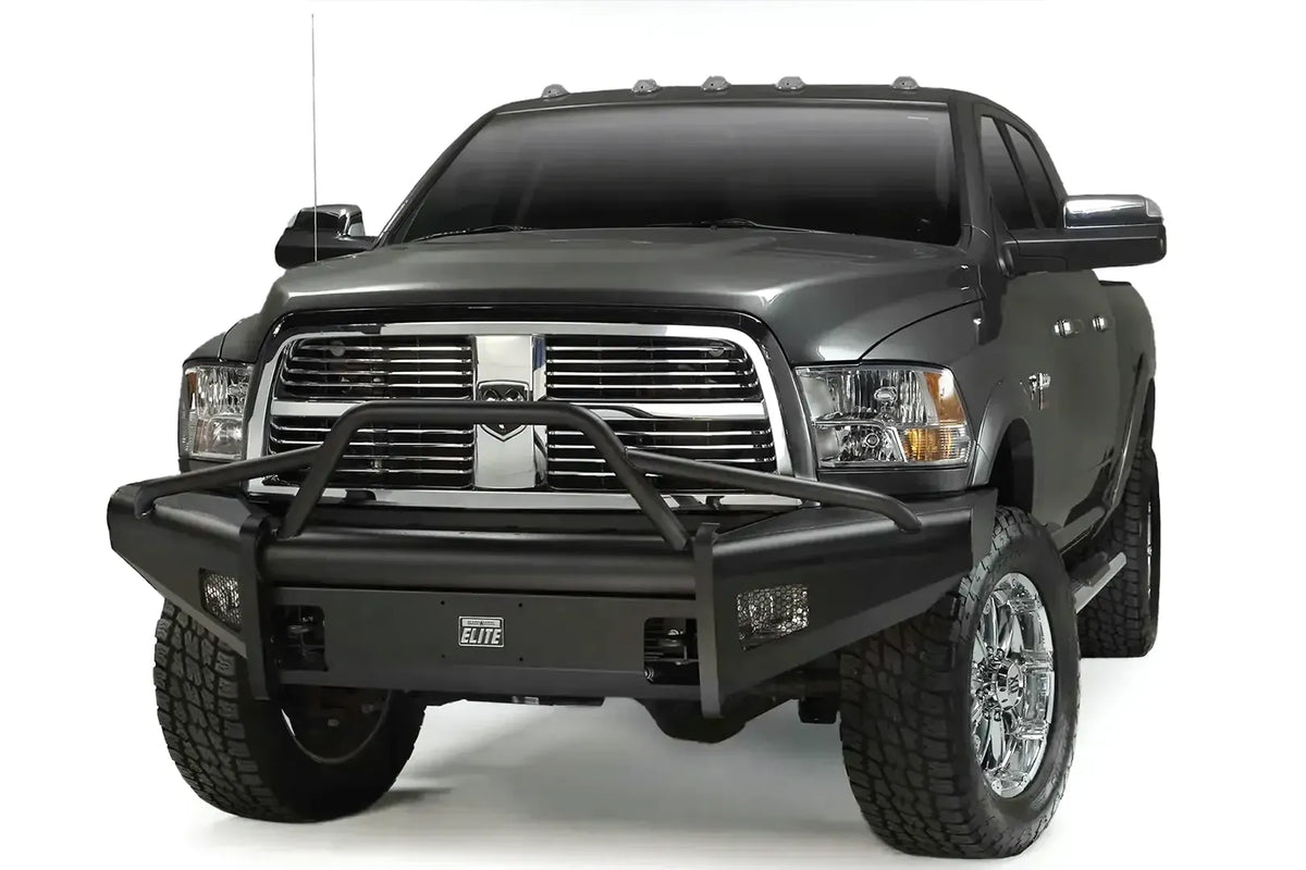 Fab Fours Black Steel Elite front bumper with pre-runner guard on a gray Ram 2500, front driver-side three-quarter view, showing the tubular pre-runner hoop, Elite badge, and integrated light openings