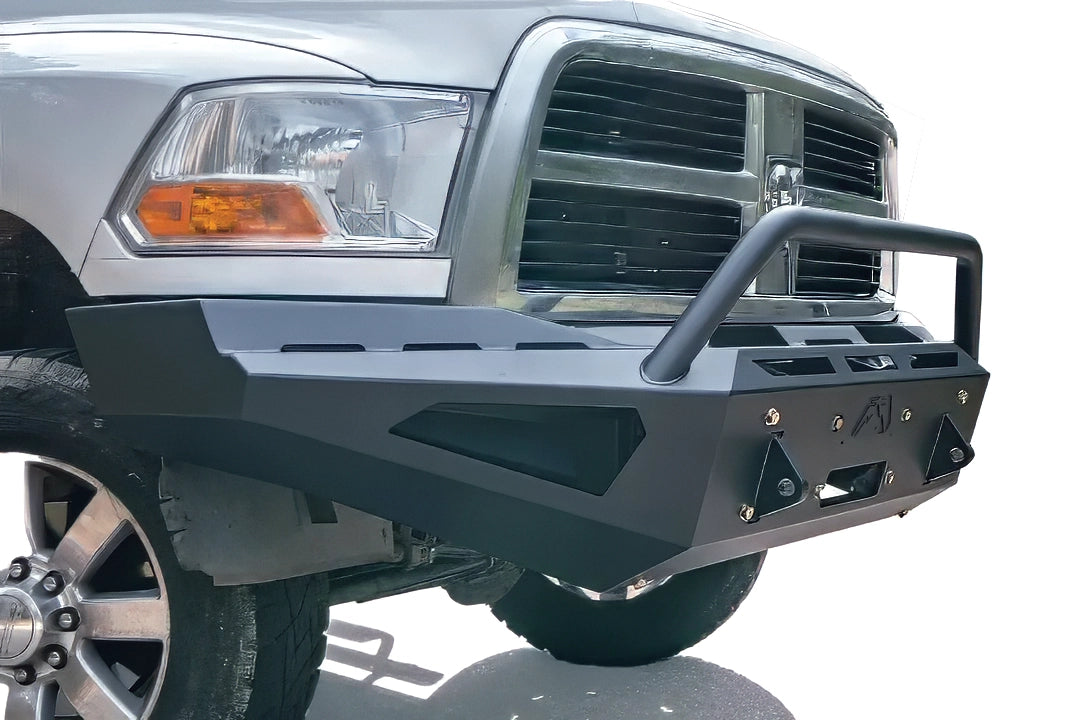 Fab Fours Red Steel front bumper with pre-runner guard on a white Ram 2500, close-up corner view, showing the pre-runner hoop, D-ring shackle mounts, and slotted top plate