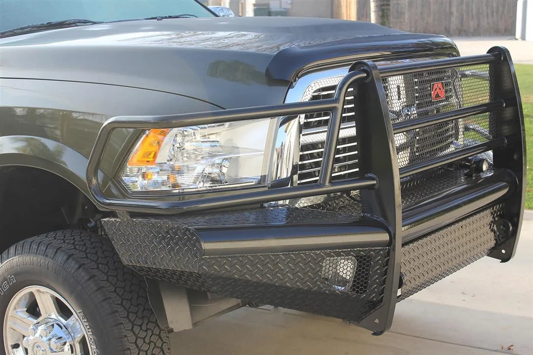 Fab Fours Black Steel front bumper with full guard on a black Ram 2500, close-up corner view outdoors, showing the headlight hoop, grille guard upright, and diamond-plate wing
