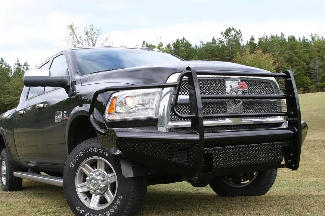 Fab Fours Black Steel front bumper with full guard on a black Ram 2500, front driver-side three-quarter view outdoors, showing the full grille guard, headlight hoops, and diamond-plate face