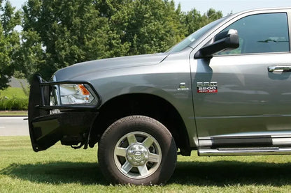 Fab Fours Black Steel front bumper with full guard on a gray Ram 2500, driver-side profile view outdoors, showing the grille guard depth, headlight hoop, and bumper wing