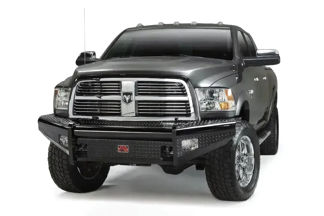 Fab Fours Black Steel front bumper on a gray Ram 2500, front driver-side three-quarter view, showing the diamond-plate face, bumper wings, and red Fab Fours badge