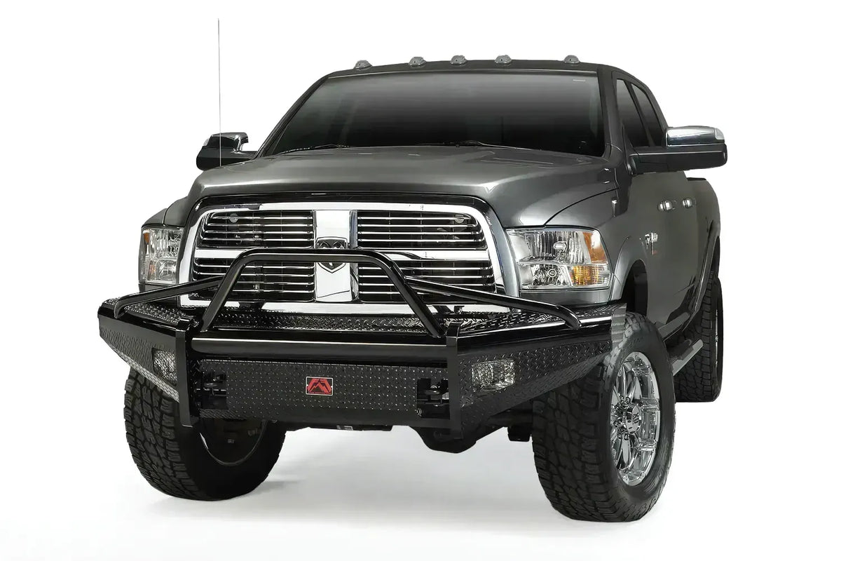 Fab Fours Black Steel front bumper with pre-runner guard on a gray Ram 2500, front driver-side three-quarter view, showing the tubular pre-runner hoop, diamond-plate face, and red Fab Fours badge