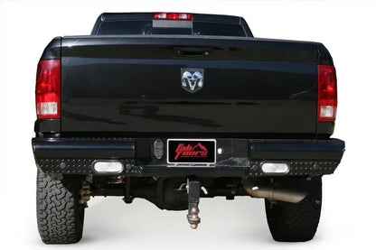 Fab Fours Black Steel rear bumper on a black Ram 1500, straight-on rear view, showing the diamond-plate face, oval lights, and center plate recess