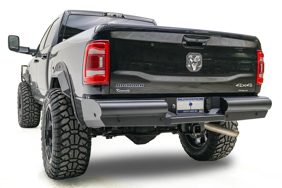 Fab Fours Black Steel Elite rear bumper on a black Ram 2500, rear driver-side three-quarter view, showing the smooth plated face, end cap, and hitch receiver