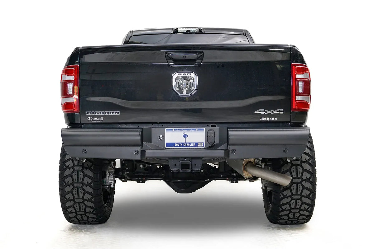 Fab Fours Black Steel Elite rear bumper on a black Ram 2500, straight-on rear view, showing the smooth plated face, center plate recess, and hitch receiver