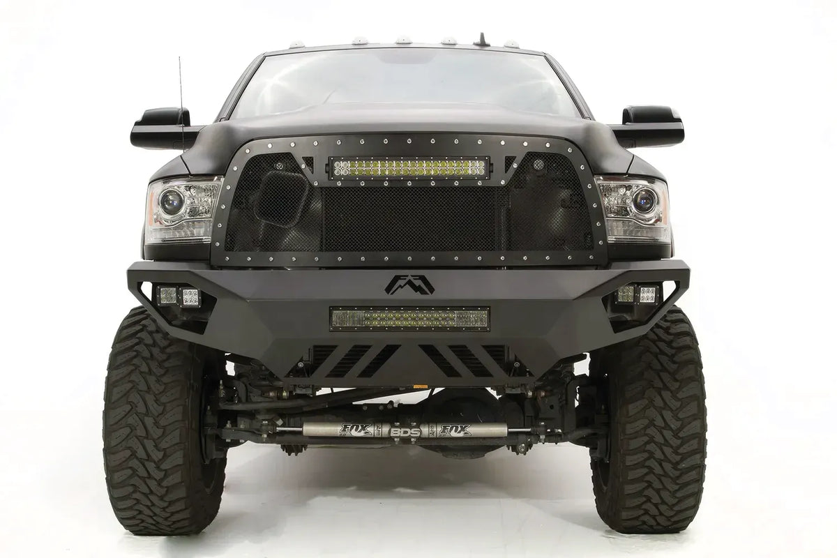 Fab Fours Vengeance front bumper on a gray Ram 2500, straight-on front view, showing the center Fab Fours logo, LED light bar, and slotted skid plate