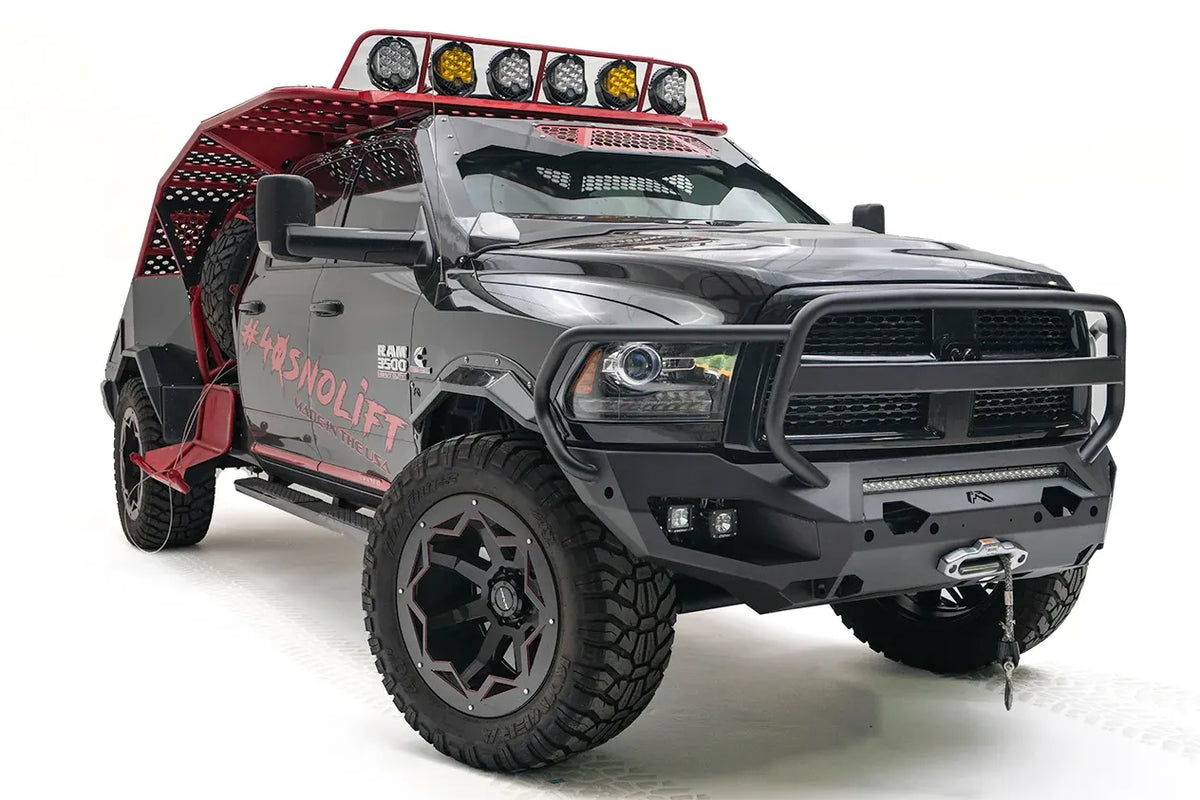 Fab Fours Matrix front bumper with full guard on a gray and black Ram 3500, front driver-side three-quarter view, showing the grille guard tubing, cube light pods, and winch with hook