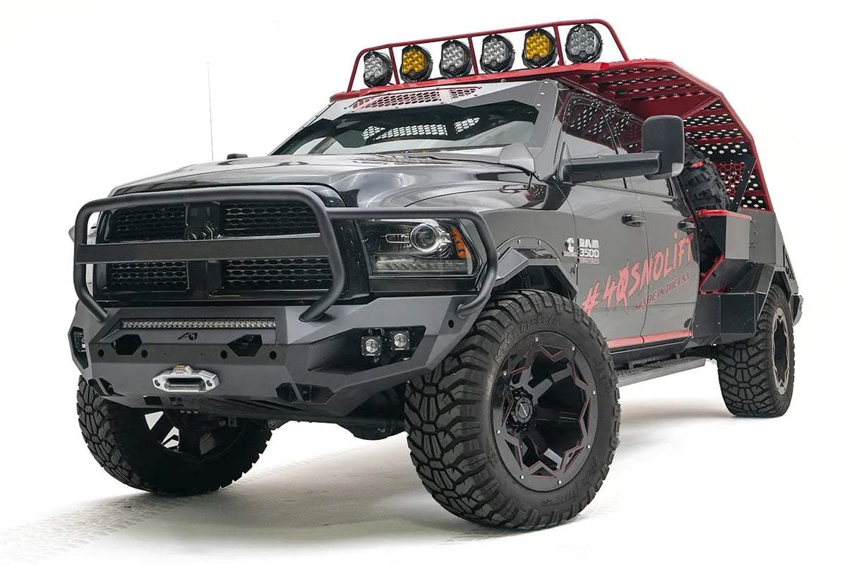 Fab Fours Matrix front bumper with full guard on a gray and black Ram 3500, front passenger-side three-quarter view, showing the tubular grille guard, LED light bar, and center winch