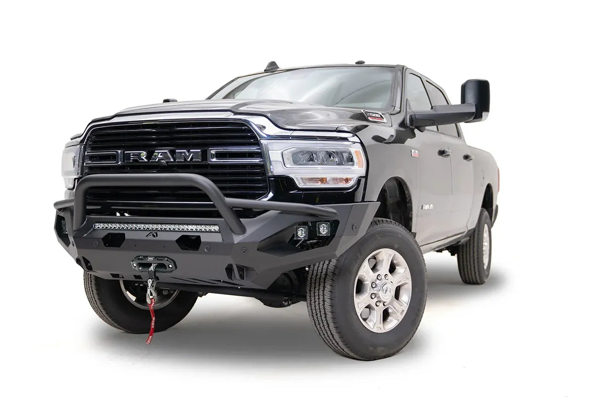 Fab Fours Matrix front bumper with pre-runner guard on a black Ram 2500, front driver-side three-quarter view, showing the tubular pre-runner bar, LED light bar, and center winch