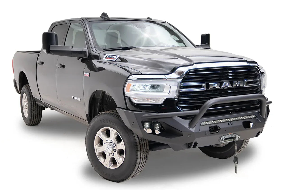 Fab Fours Matrix front bumper with pre-runner guard on a black Ram 2500, front passenger-side three-quarter view, showing the pre-runner bar, cube light pods, and winch with hook