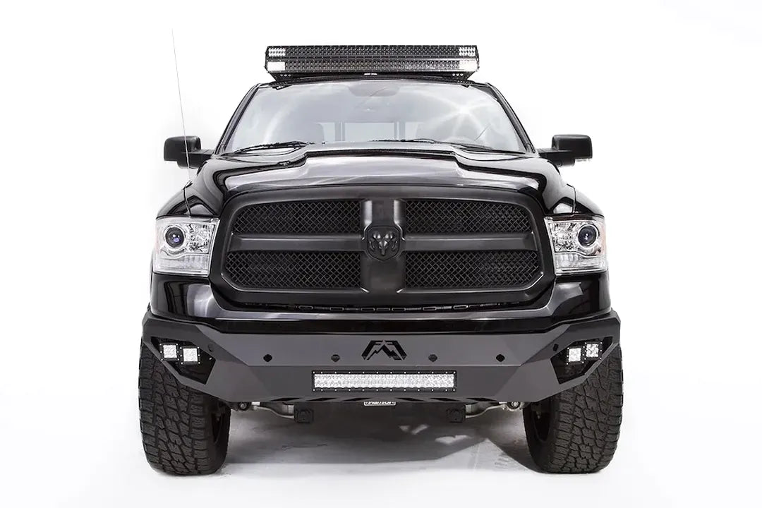 Fab Fours Vengeance front bumper on a black Ram 1500, straight-on front view, showing the center Fab Fours logo, LED light bar, and cube light pods
