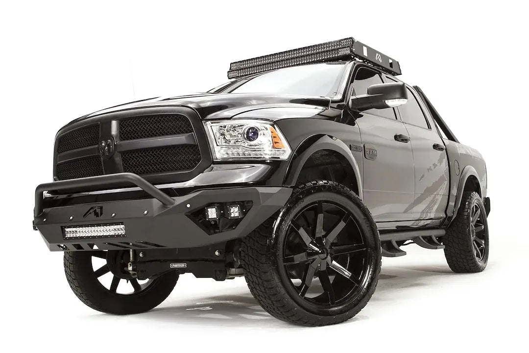 Fab Fours Vengeance front bumper with pre-runner guard on a dark gray Ram 1500, front driver-side three-quarter view, showing the pre-runner hoop, integrated LED cube lights and lower light bar