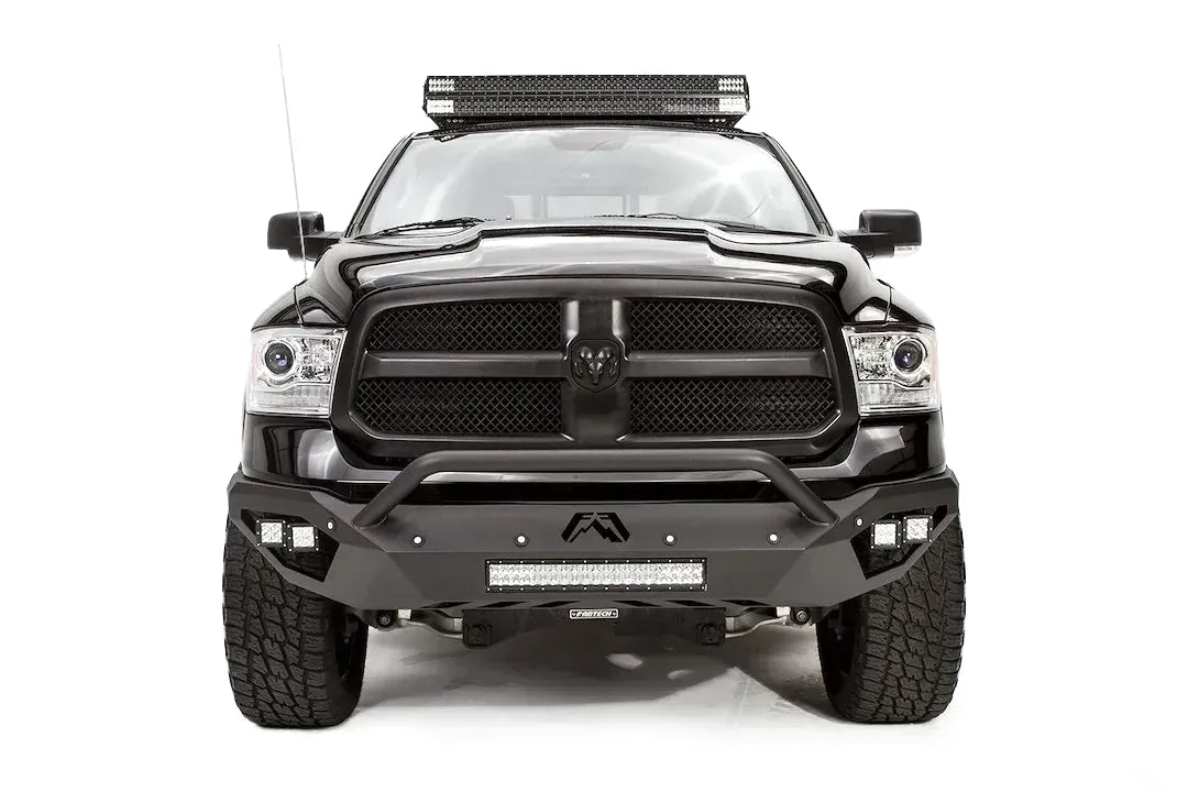 Fab Fours Vengeance front bumper with pre-runner guard on a black Ram 1500, straight-on front view, showing the pre-runner hoop, center logo plate, cube lights and lower light bar