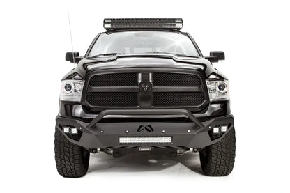 Fab Fours Vengeance front bumper with pre-runner guard on a black Ram 1500, straight-on front view, showing the pre-runner hoop, center logo plate, cube lights and lower light bar