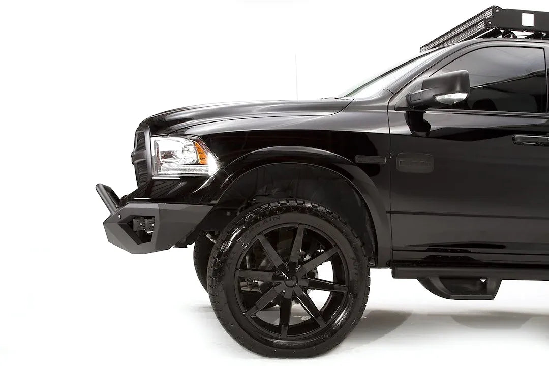 Fab Fours Vengeance front bumper with pre-runner guard on a black Ram 1500, close front driver-side corner view, showing the pre-runner tube, bumper wing and low-profile end cap