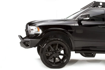 Fab Fours Vengeance front bumper with pre-runner guard on a black Ram 1500, close front driver-side corner view, showing the pre-runner tube, bumper wing and low-profile end cap