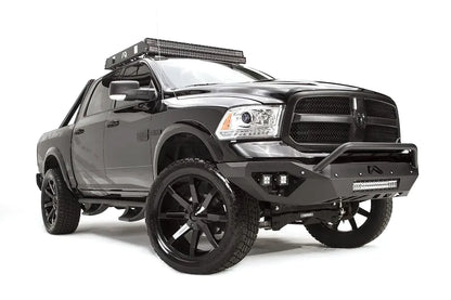 Fab Fours Vengeance front bumper with pre-runner guard on a dark gray Ram 1500, front passenger-side three-quarter view, showing the pre-runner hoop, cube light pods and angled bumper ends