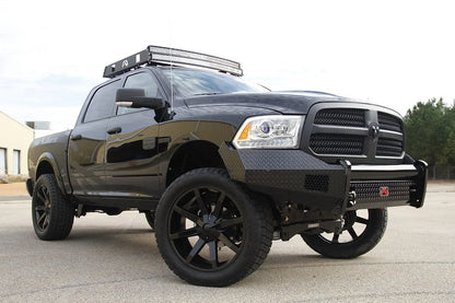 Fab Fours Black Steel front bumper on a black Ram 1500, front passenger-side three-quarter view outdoors, showing the diamond-plate face, wrap-around wings and center tube