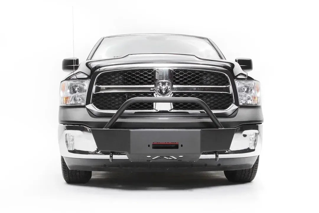 Fab Fours winch mount on a dark gray Ram 1500, straight-on front view, showing the winch plate with fairlead opening, tube hoop and factory chrome bumper ends