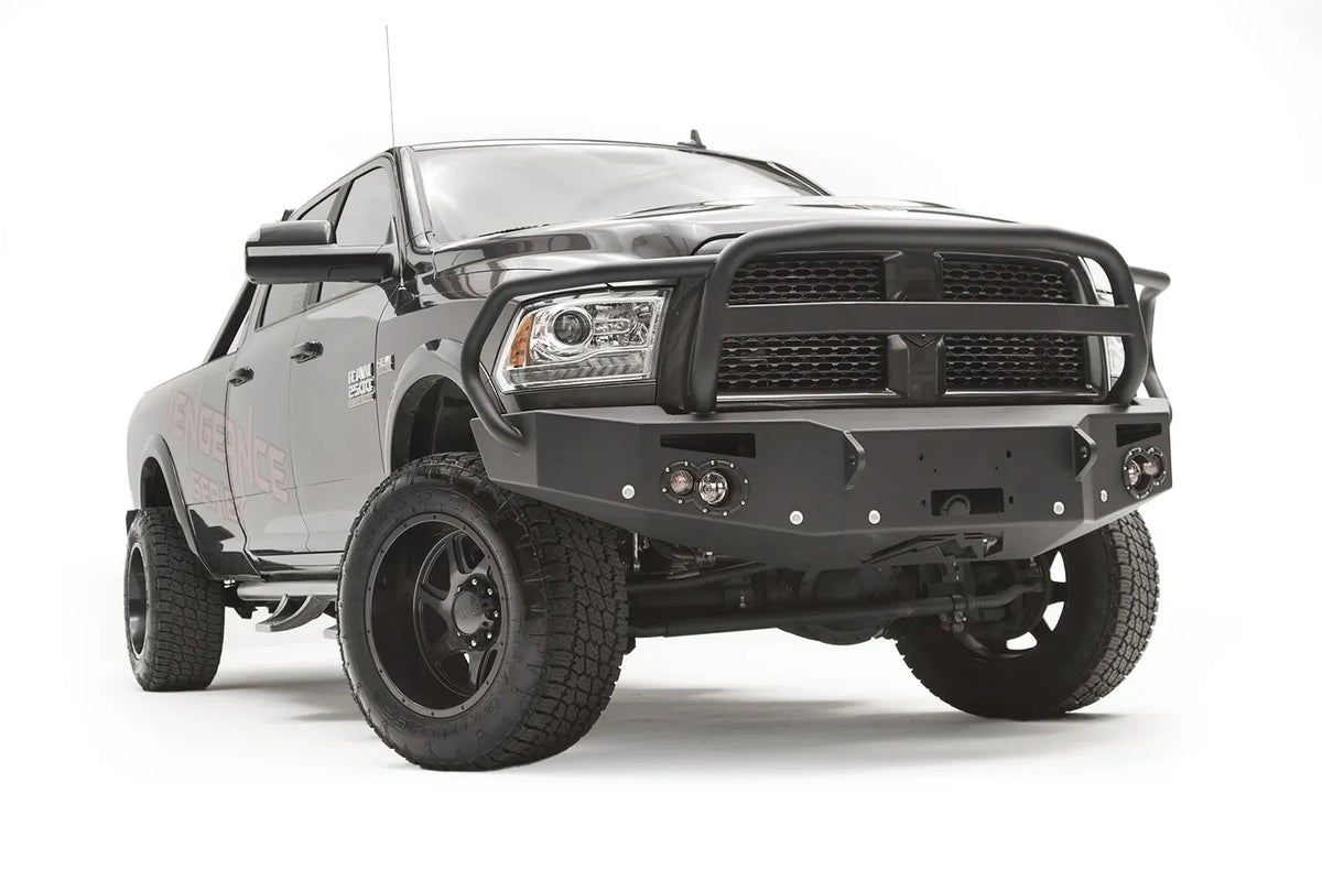 Fab Fours Premium front bumper with full guard on a black Ram 2500, front passenger-side three-quarter view, showing the full grille guard hoop, round lights and winch mount