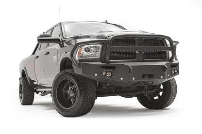 Fab Fours Premium front bumper with full guard on a black Ram 2500, front passenger-side three-quarter view, showing the full grille guard hoop, round lights and winch mount
