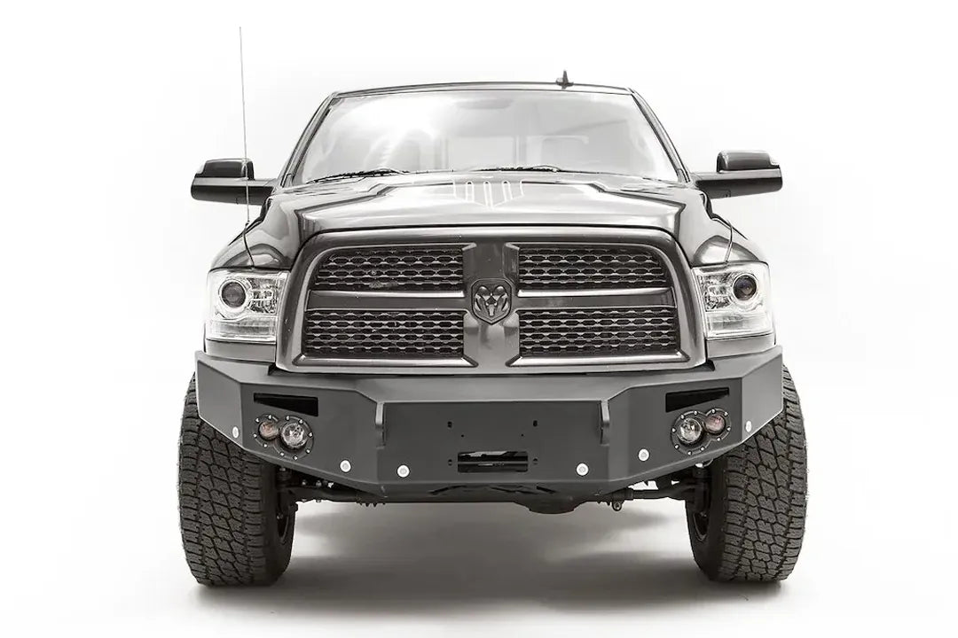 Fab Fours Premium front bumper on a dark gray Ram 2500, straight-on front view, showing the winch mount opening, round lights and D-ring mounts