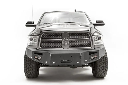 Fab Fours Premium front bumper on a dark gray Ram 2500, straight-on front view, showing the winch mount opening, round lights and D-ring mounts