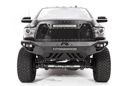 Fab Fours Vengeance front bumper on a dark gray lifted Ram 2500, straight-on front view, showing the integrated light bar, cube light pods and slotted skid plate