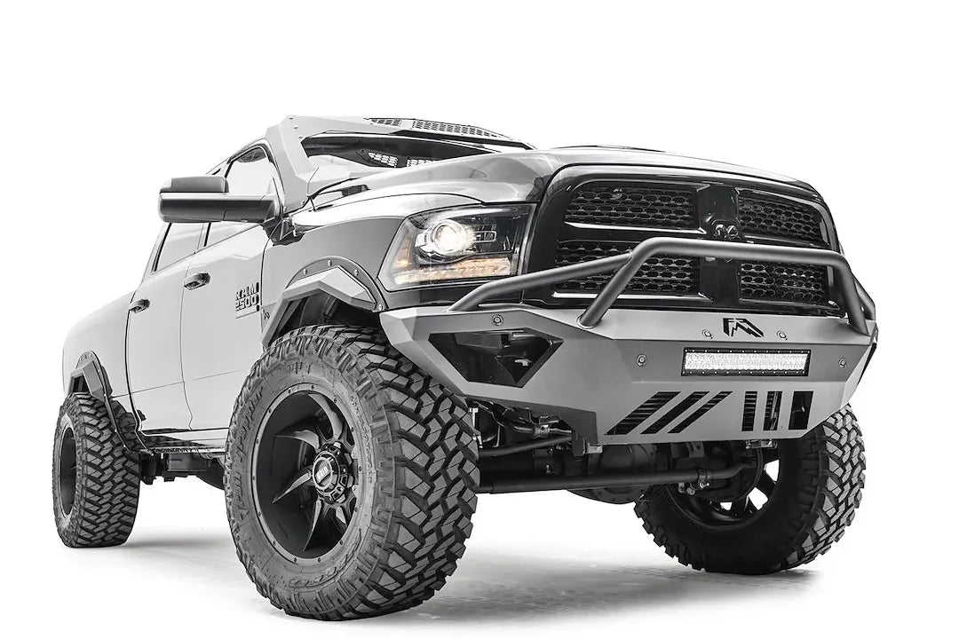 Fab Fours Open Fender front bumper on a gray lifted Ram 2500, front passenger-side three-quarter view, showing the pre-runner hoop, integrated light bar and open fender cutaway