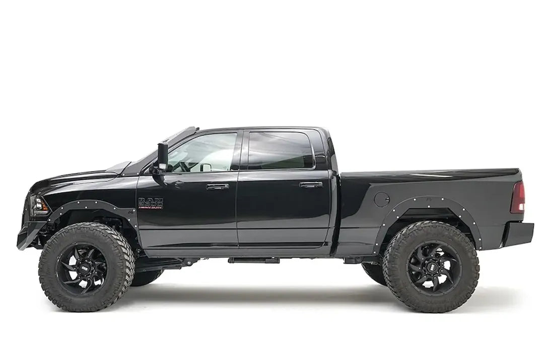 Fab Fours front bumper on a black lifted Ram 2500, driver-side profile view, showing the bumper's low profile and fender clearance